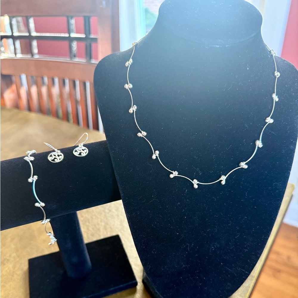 Delicate, silver necklace, bracelet, and earrings set.